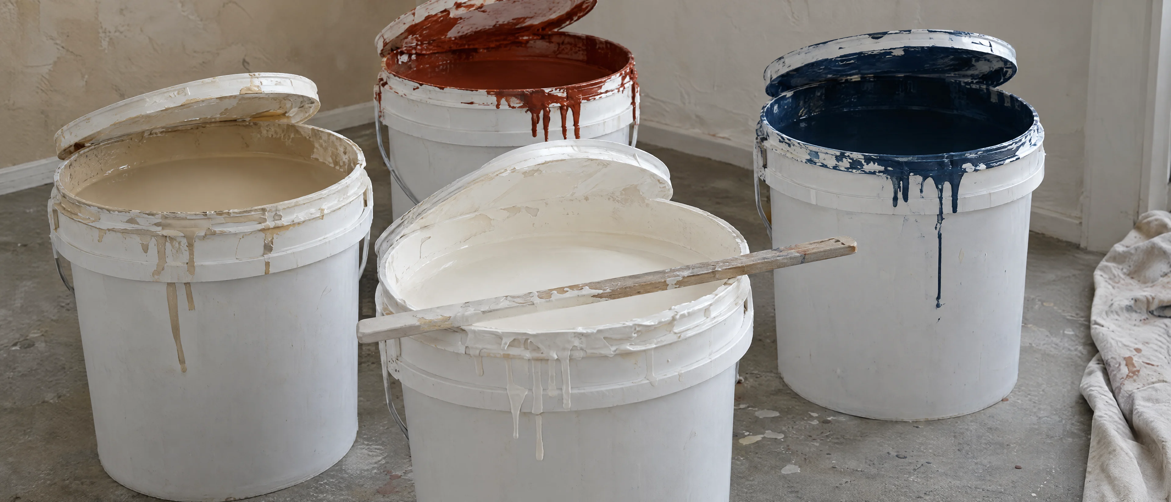 Offene Farbeimer mit Farbresten in Weiß, Ziegelrot und Marineblau