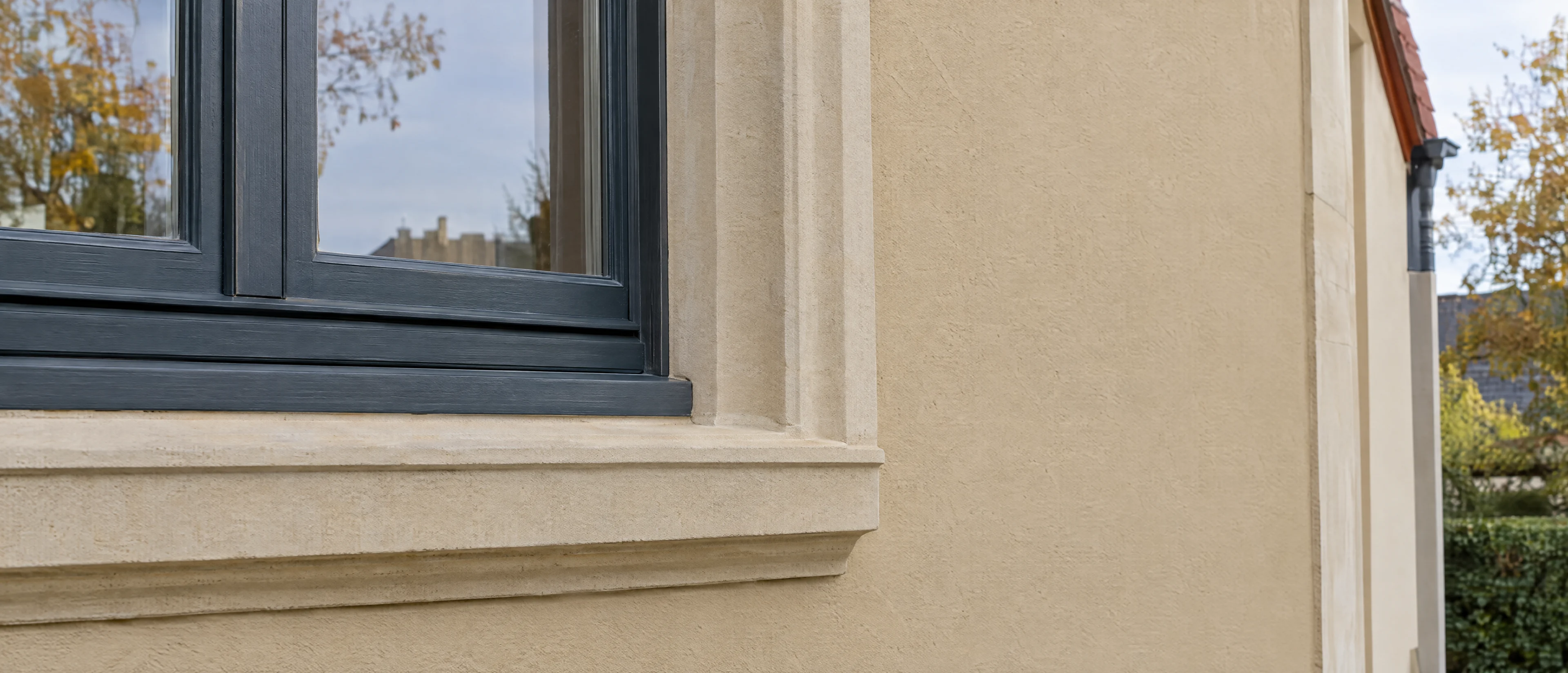 Frisch gestrichene Putzfassade mit hellem Sandsteingewände am Fenster