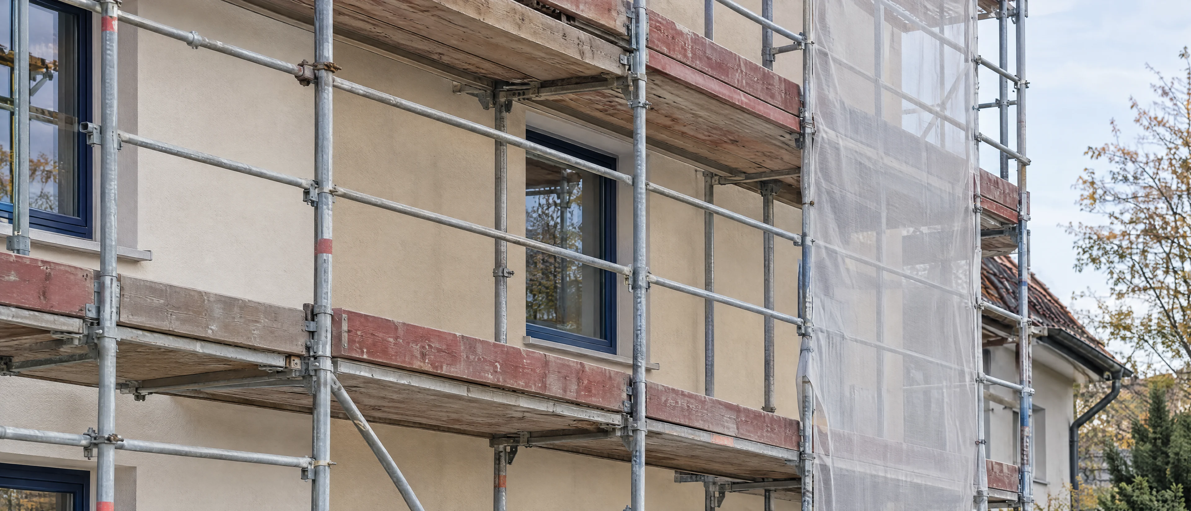 Fassadengerüst mit Schutznetz vor einer verputzten Wand