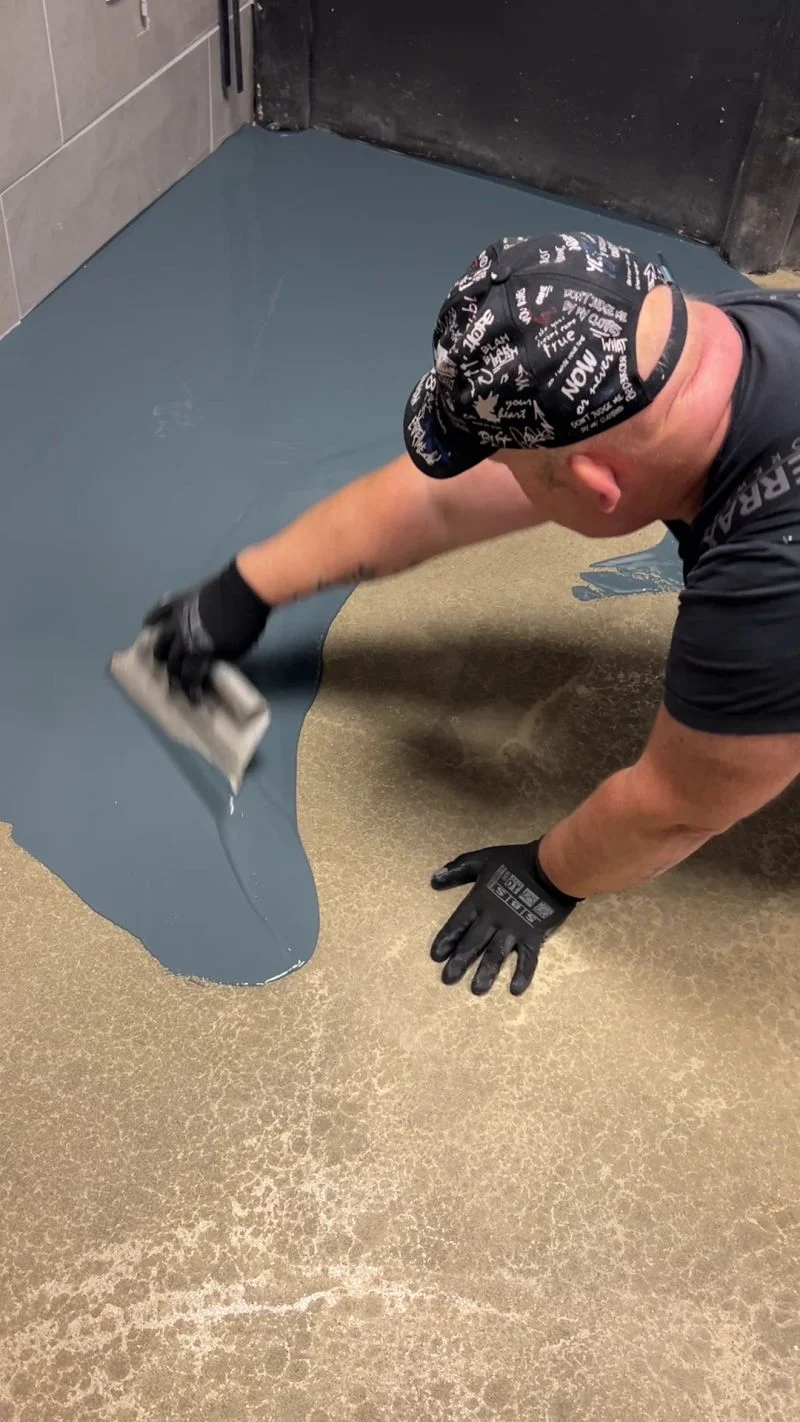 Hand in Arbeitshandschuh beim Verarbeiten einer Bodenbeschichtung